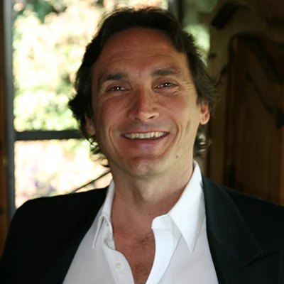 Viktor Grant, smiling, in a white shirt and a dark jacket.